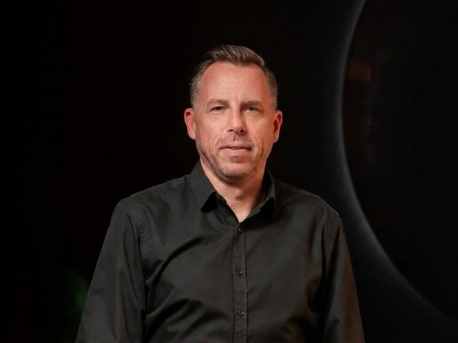 Foto do Felipe Schmitt-Fleischer, estrategista de marcas, palestrante e cofundador da Evolgo. Ele tem curtos e grisalhos, e usa camisa preta, em pé diante de um fundo escuro.