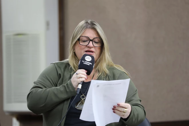 Vereadora Sandra Bonetto fala ao microfone da TV Câmara Caxias enquanto segura documentos durante sessão do Legislativo municipal.