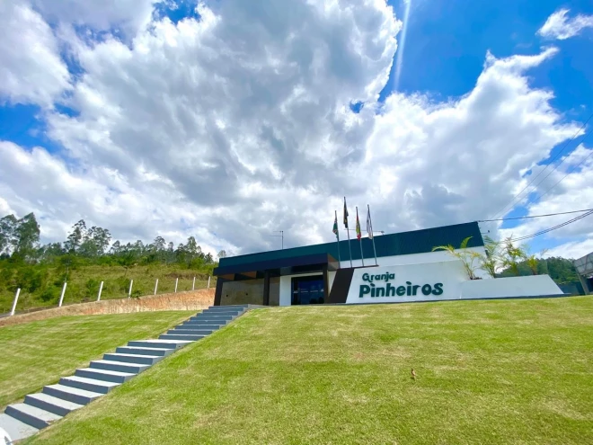destaca-se um amplo gramado bem cuidado que conduz à entrada principal do prédio por meio de uma escadaria de concreto. O edifício apresenta arquitetura contemporânea, com linhas retas, fachada nas cores branca, preta e cinza e o nome "Granja Pinheiros" e