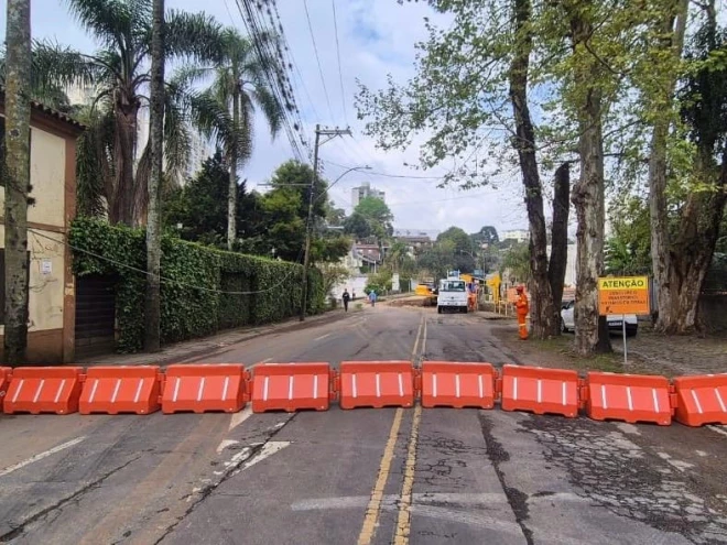 Trecho da Rua Luiz Covolan, em Caxias do Sul, está bloqueado por barreiras de trânsito durante as obras do Túnel Matteo Gianella. Ao fundo, trabalhadores e máquinas atuam na área da intervenção.