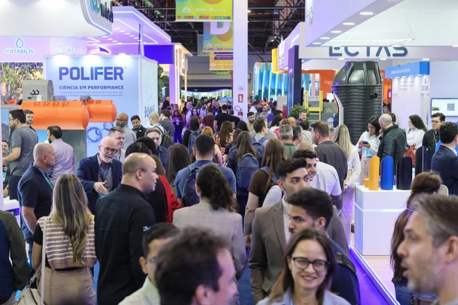 Visitantes circulam entre estandes de empresas durante feira de saneamento ambiental, com exposição de equipamentos, reservatórios e soluções para o setor. O evento reúne profissionais e representantes de diferentes organizações.
