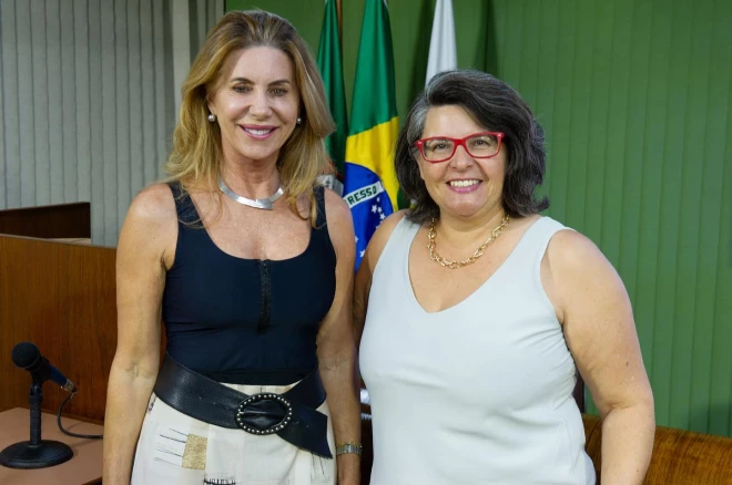 A presidente da ARI Serra Gaúcha, Lisete Alberici Oselame e a vice Adriana Silva posam lado a lado em ambiente institucional, diante de bandeiras do Brasil.