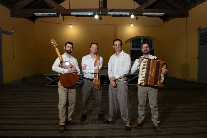 Os quatro músicos do grupo Yangos. Um deles segura um violão e outro aparece com um acordeon.